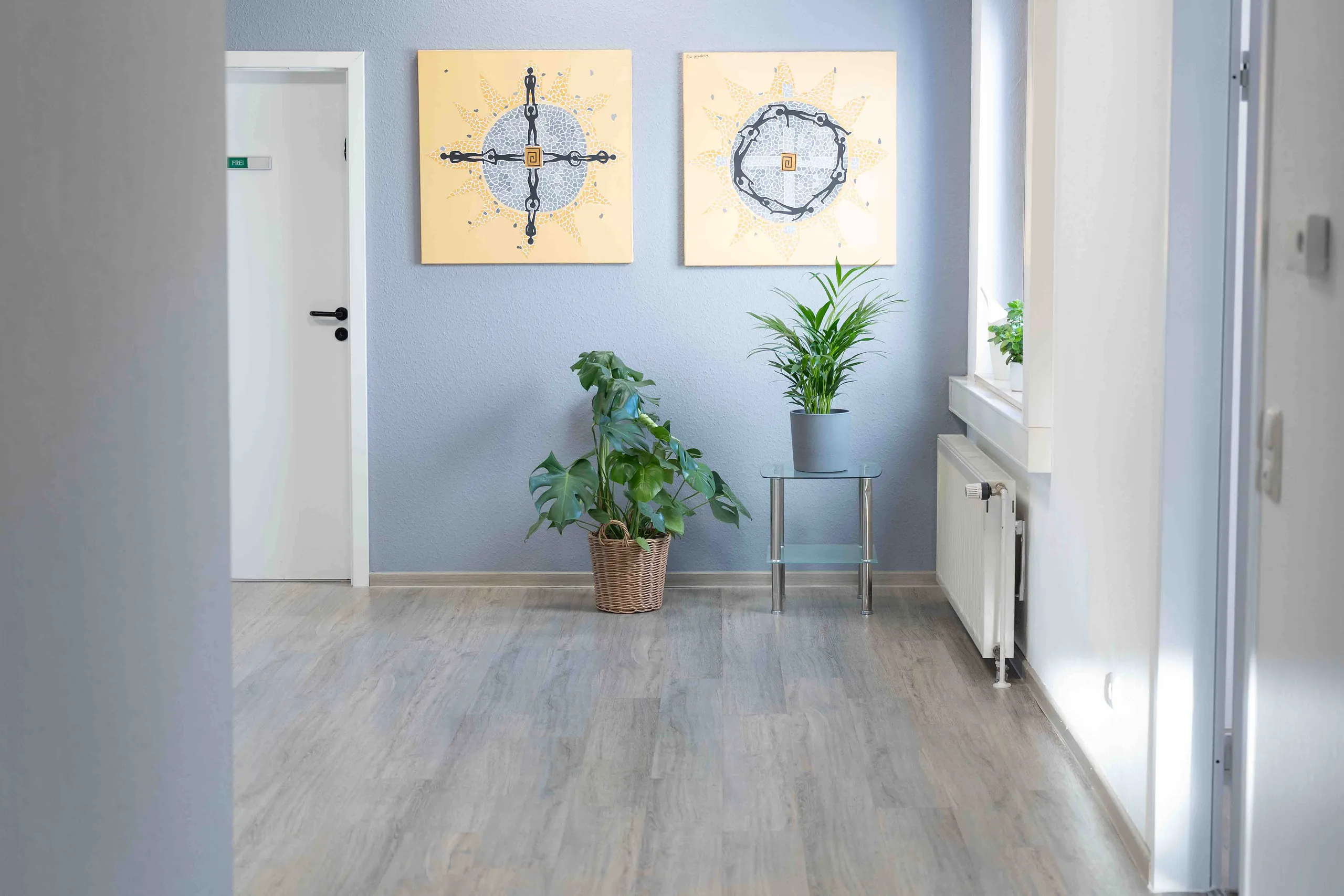 Flur der Praxis Otero mit Mosaik-Kunstwerken und Pflanzen