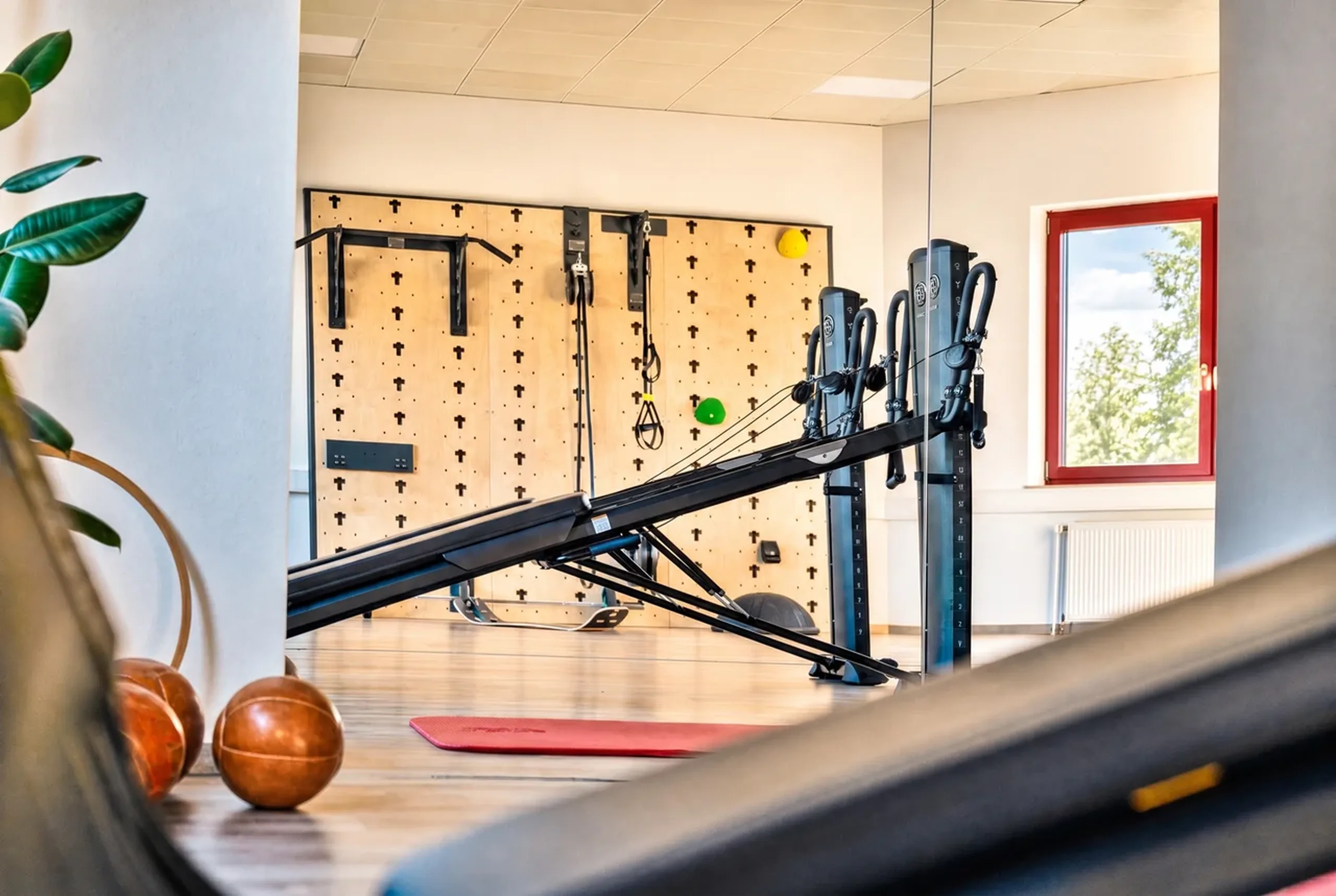 Trainingsraum der Praxis Otero in warmem Licht mit Spiegelwand und Medizinbällen